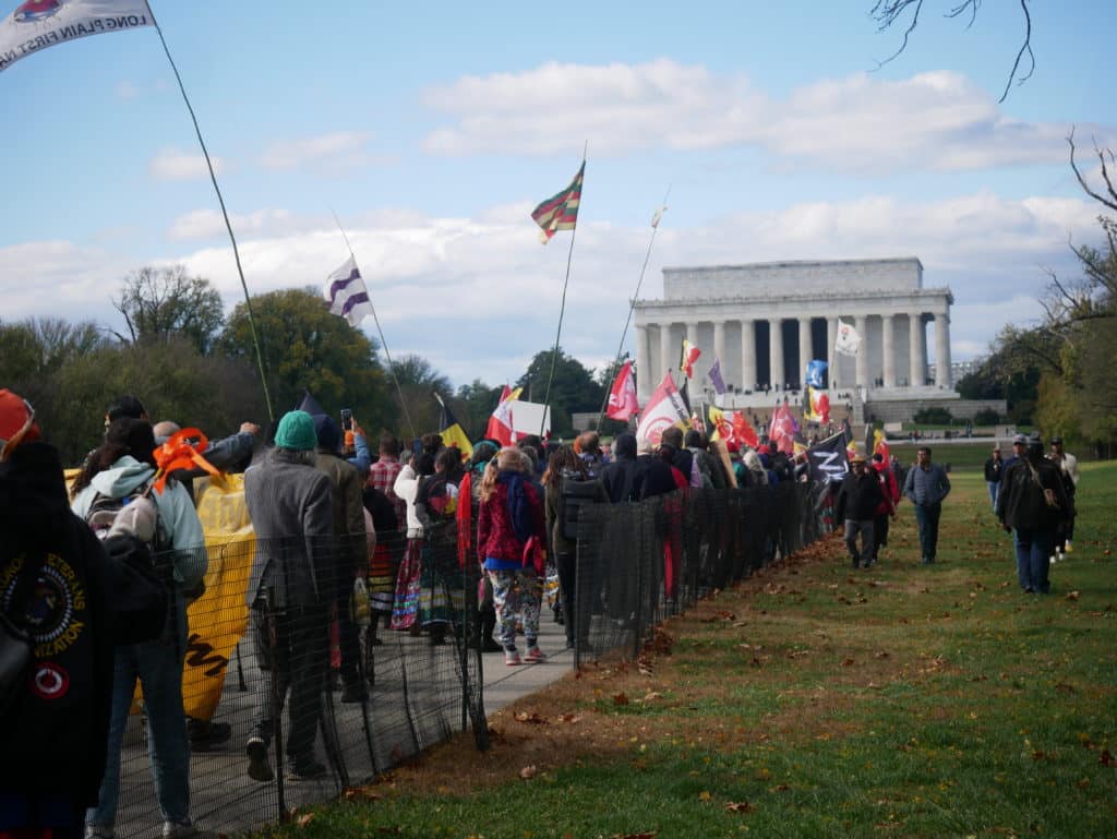 Supporters of Native American rights activist and political prisoner Leonard Peltier march toward the Lincoln Memorial, waving flags for the American Indian Movement, to demand President Joe Biden grant his release from federal prison. (Photo by Sam Bishop.)